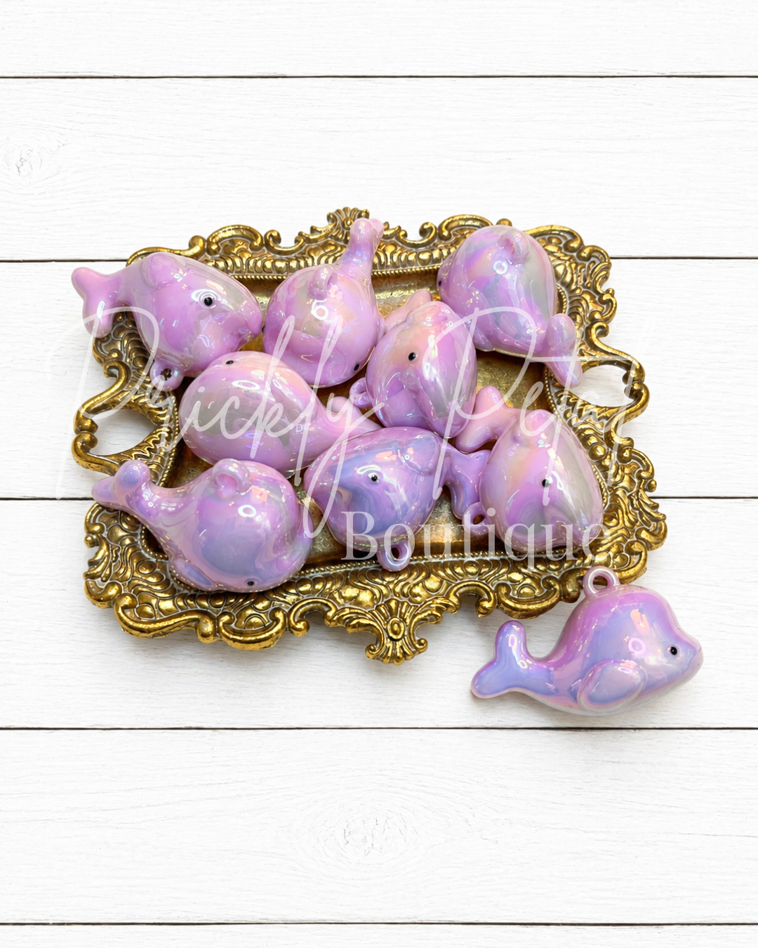 purple whale charm on gold tray against white background