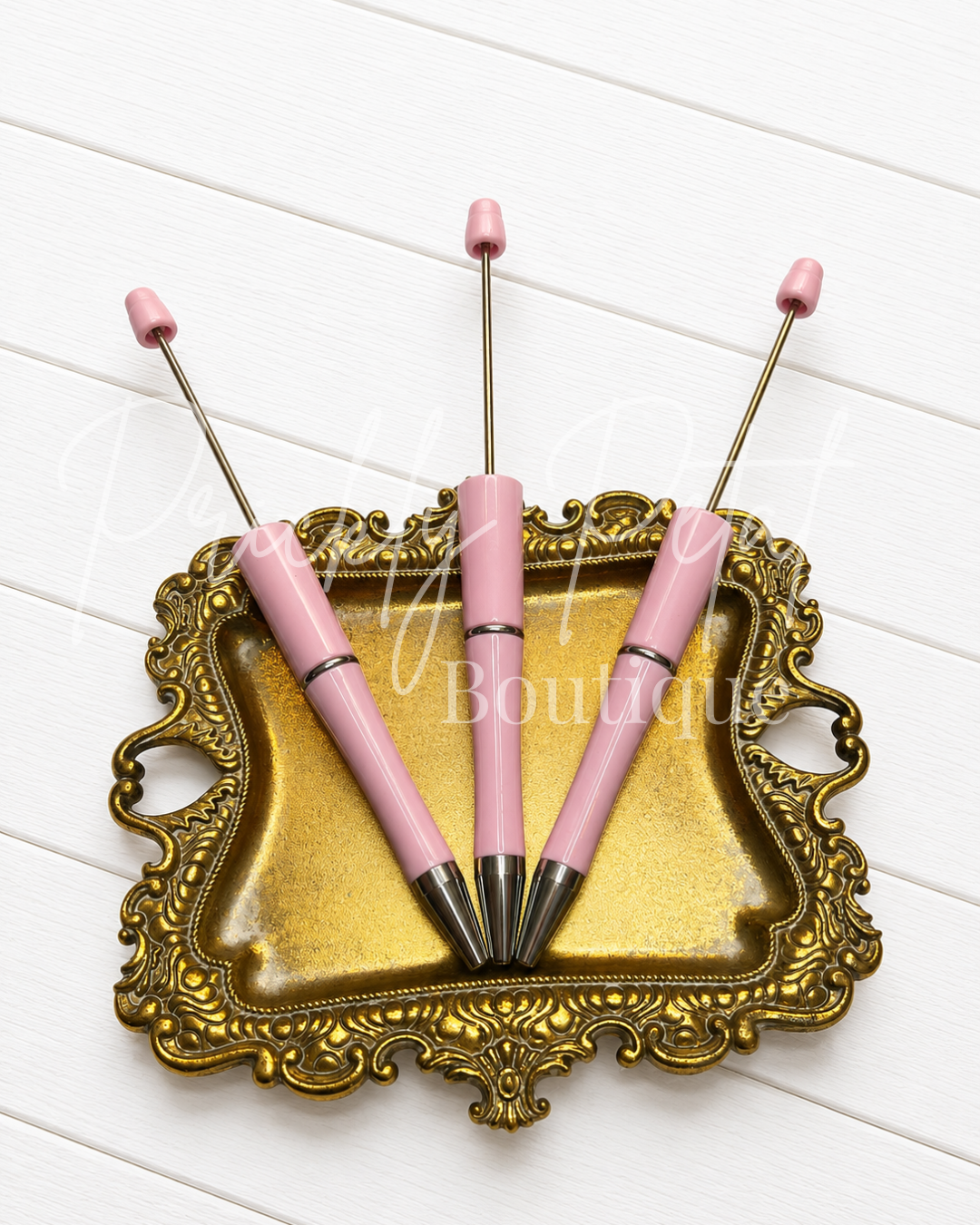 light pink beadable pens on gold tray against white wood
