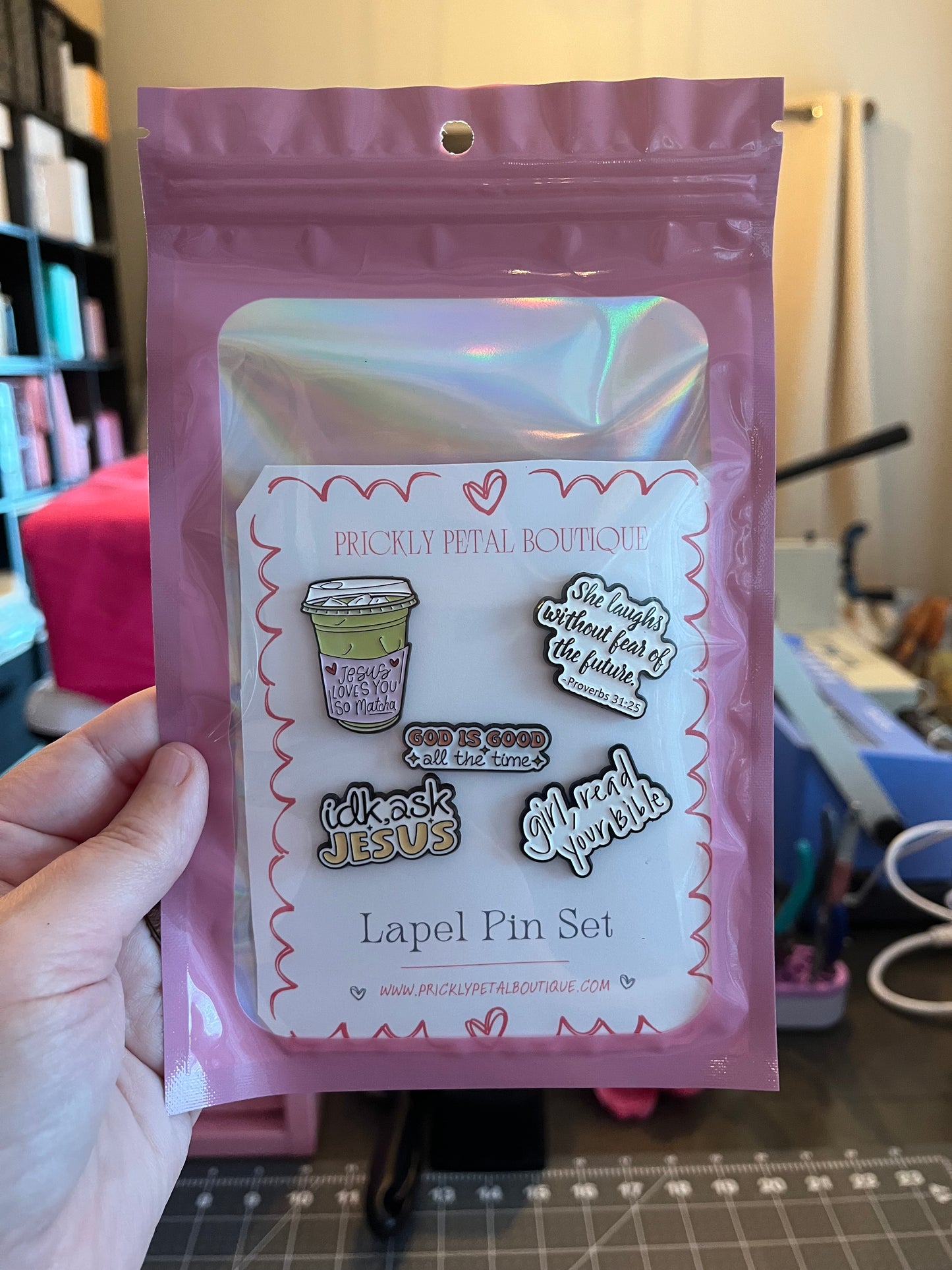 Packaged lapel pin set held by a hand with a blurred background