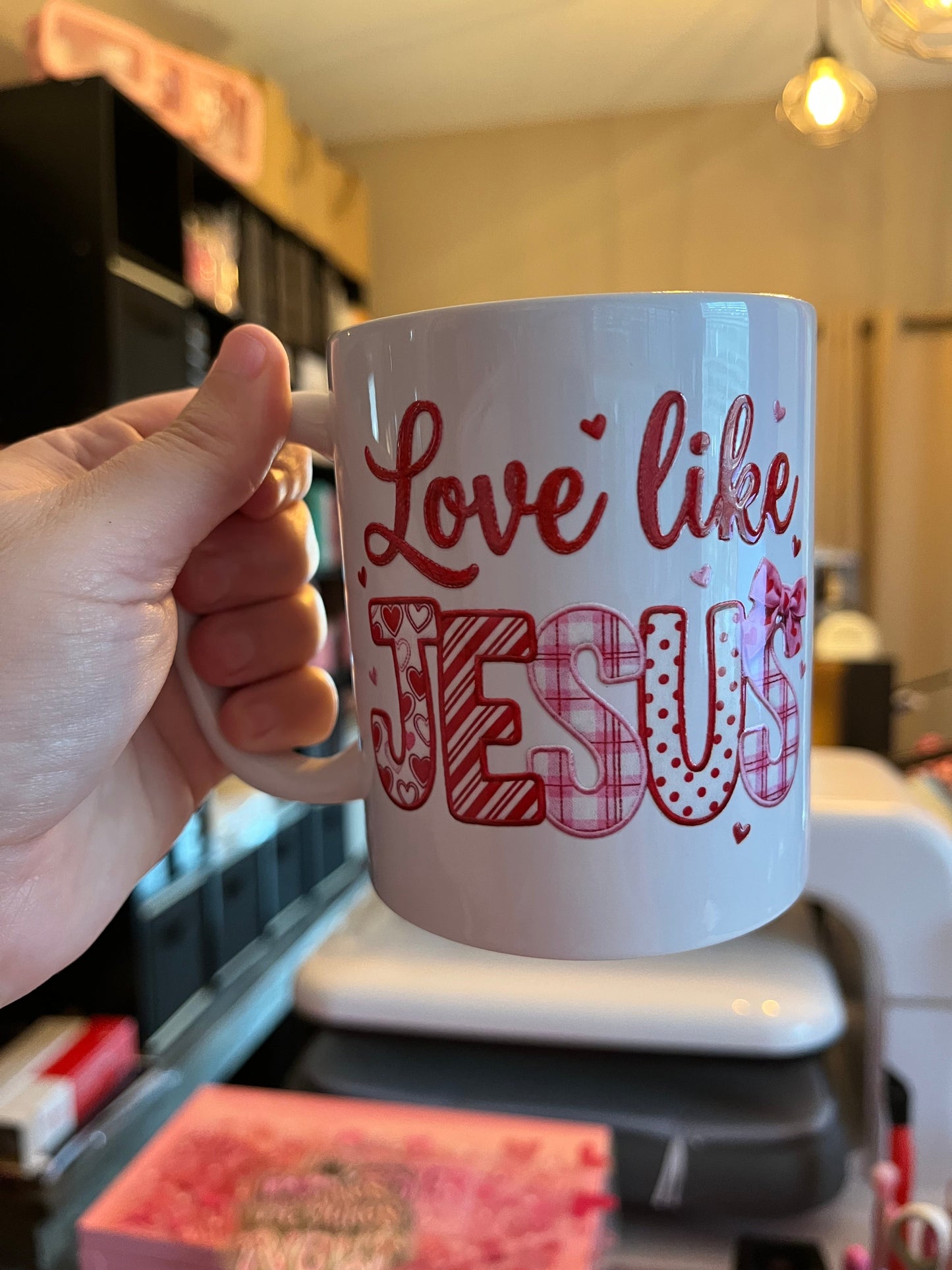 Mug with 'Love like Jesus' text held by a hand in a kitchen setting