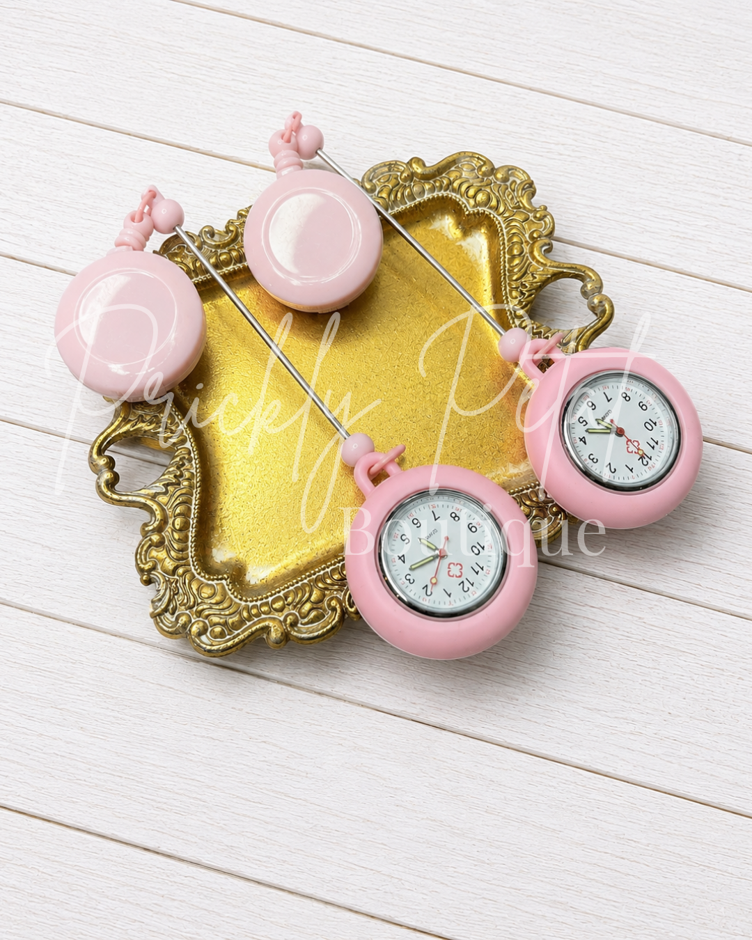 pink beadable badge reel watch on gold tray against white background