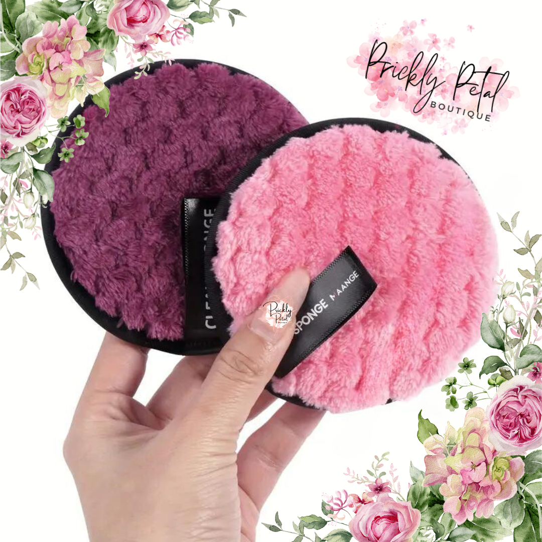 A hand holding two round makeup remover pads in pink and purple colors, with a floral background.