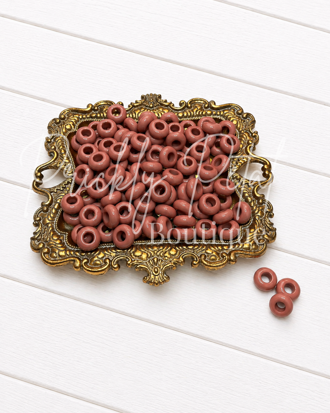 12mm spacer beads on gold tray against white wood background