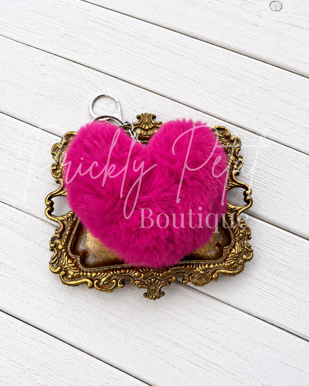hot pink fur keychain on gold tray on white wood background
