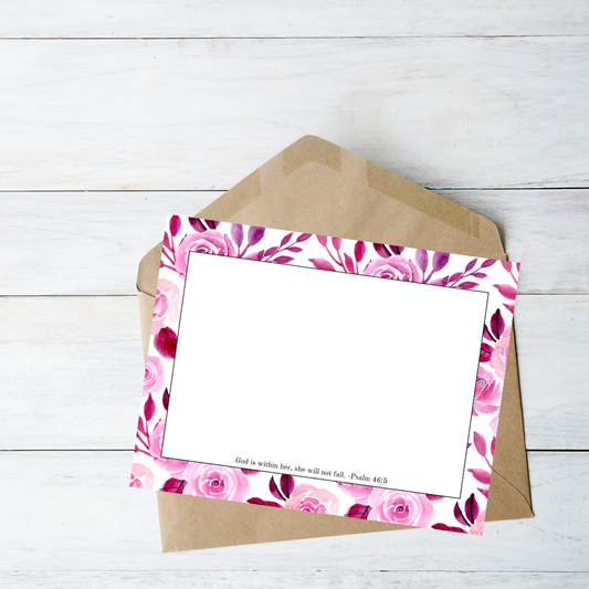 Floral card with pink roses and a brown envelope on a light wooden surface