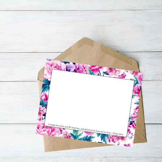 Floral card with a brown envelope on a light wooden surface