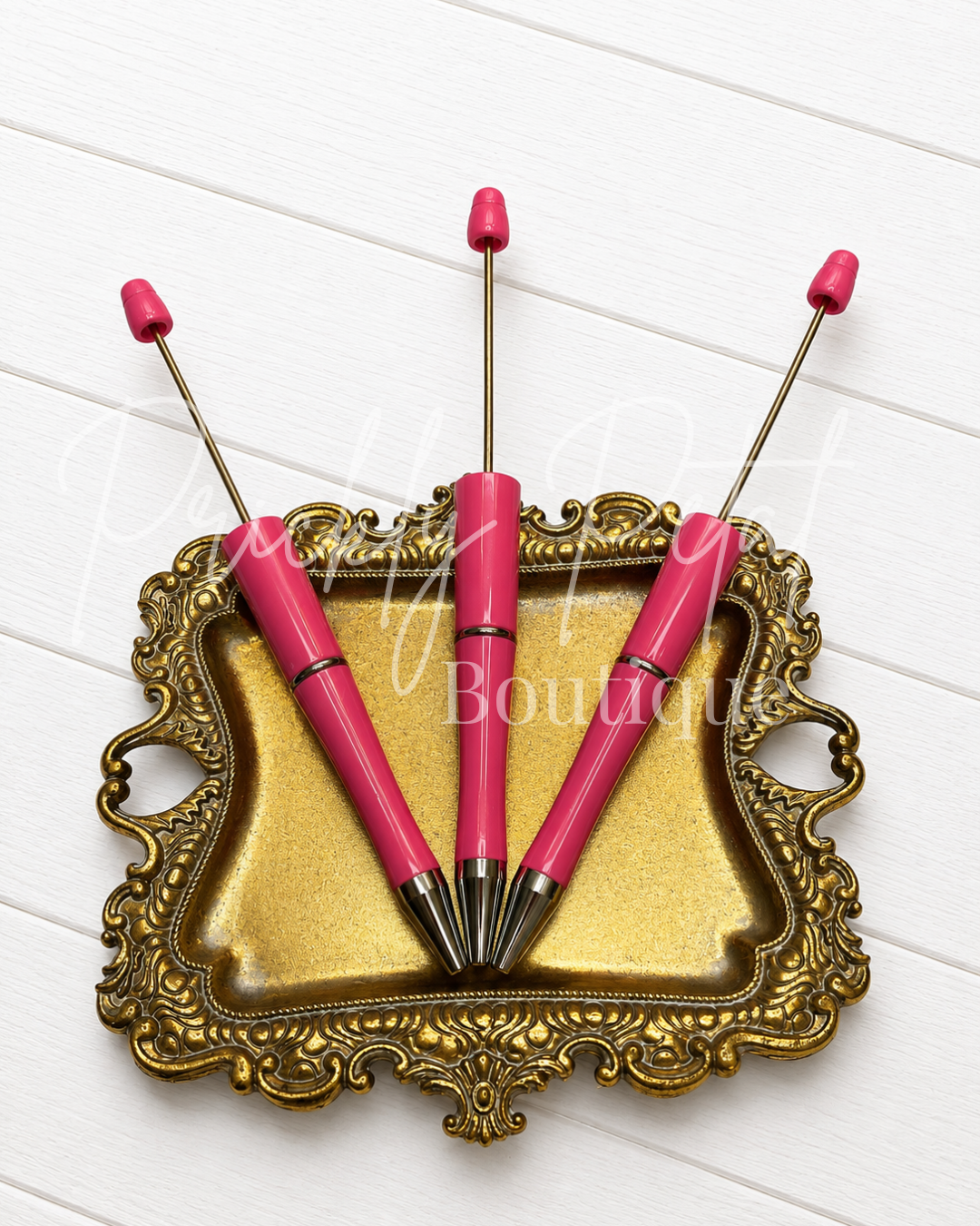 bright pink beadable pen on gold tray against white wood