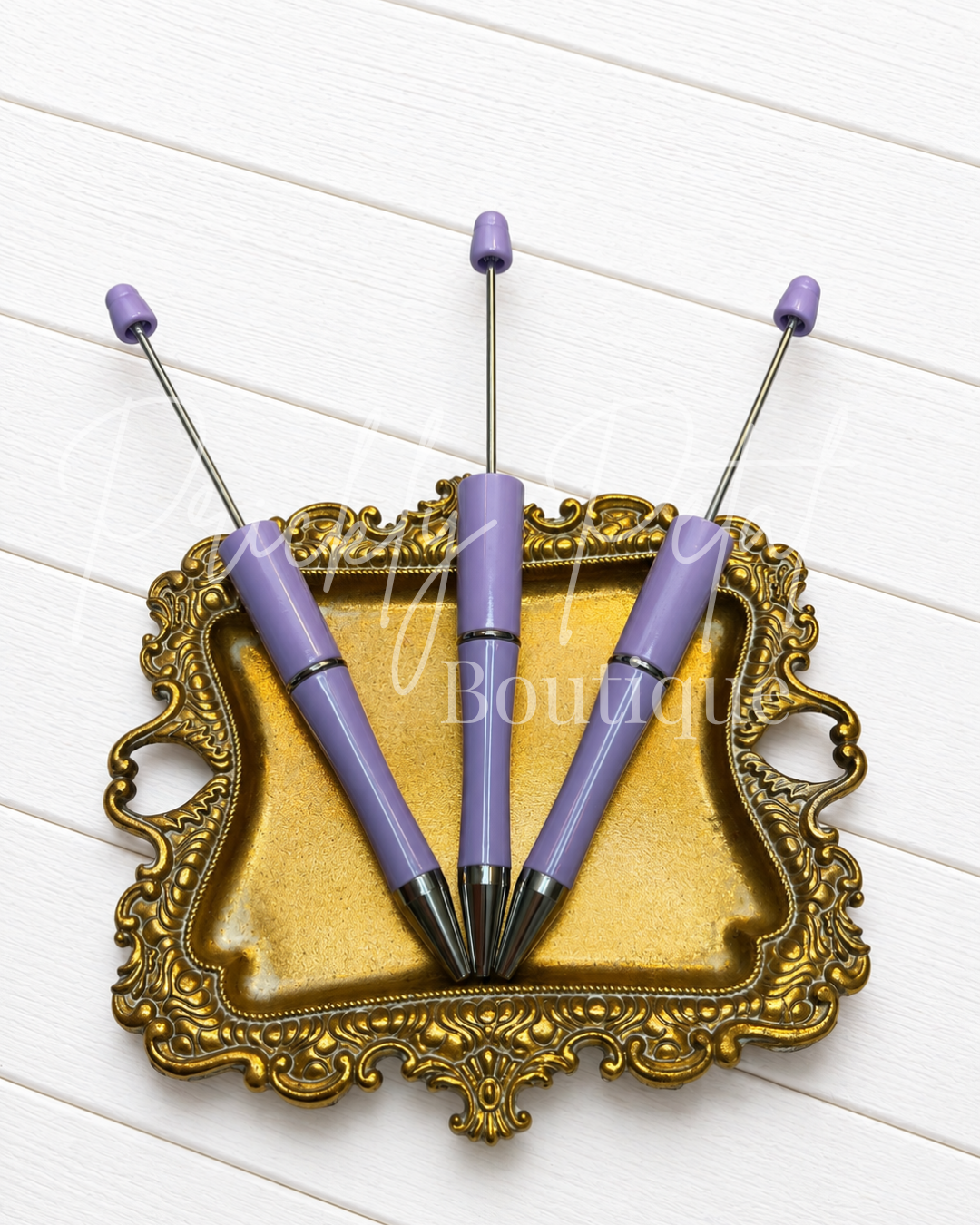 light purple beadable pen on gold tray against white wood