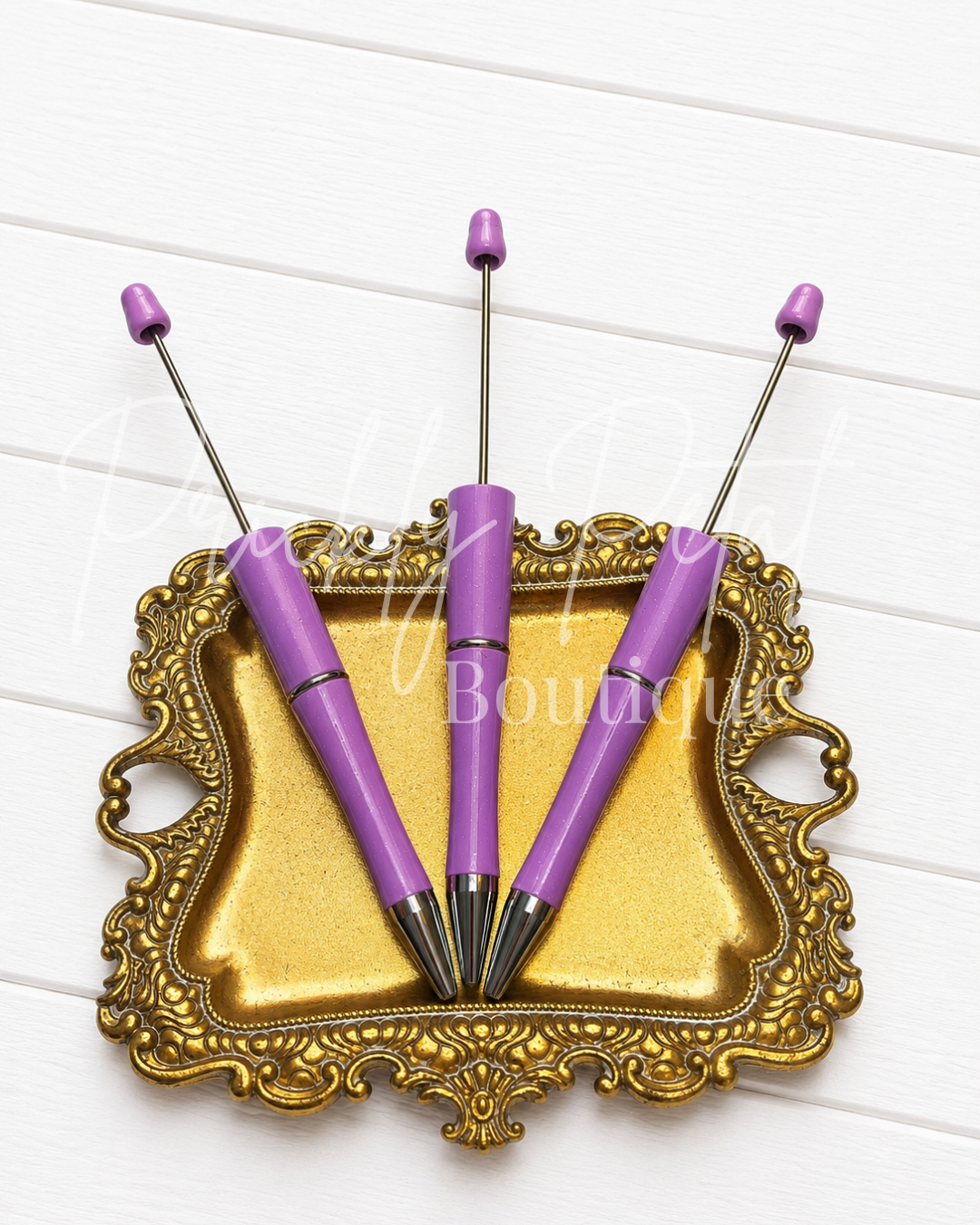 purple sparkle beadable pen on gold tray against white wood