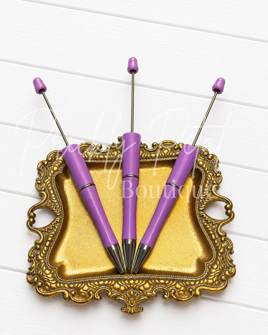 purple sparkle beadable pen on gold tray against white wood
