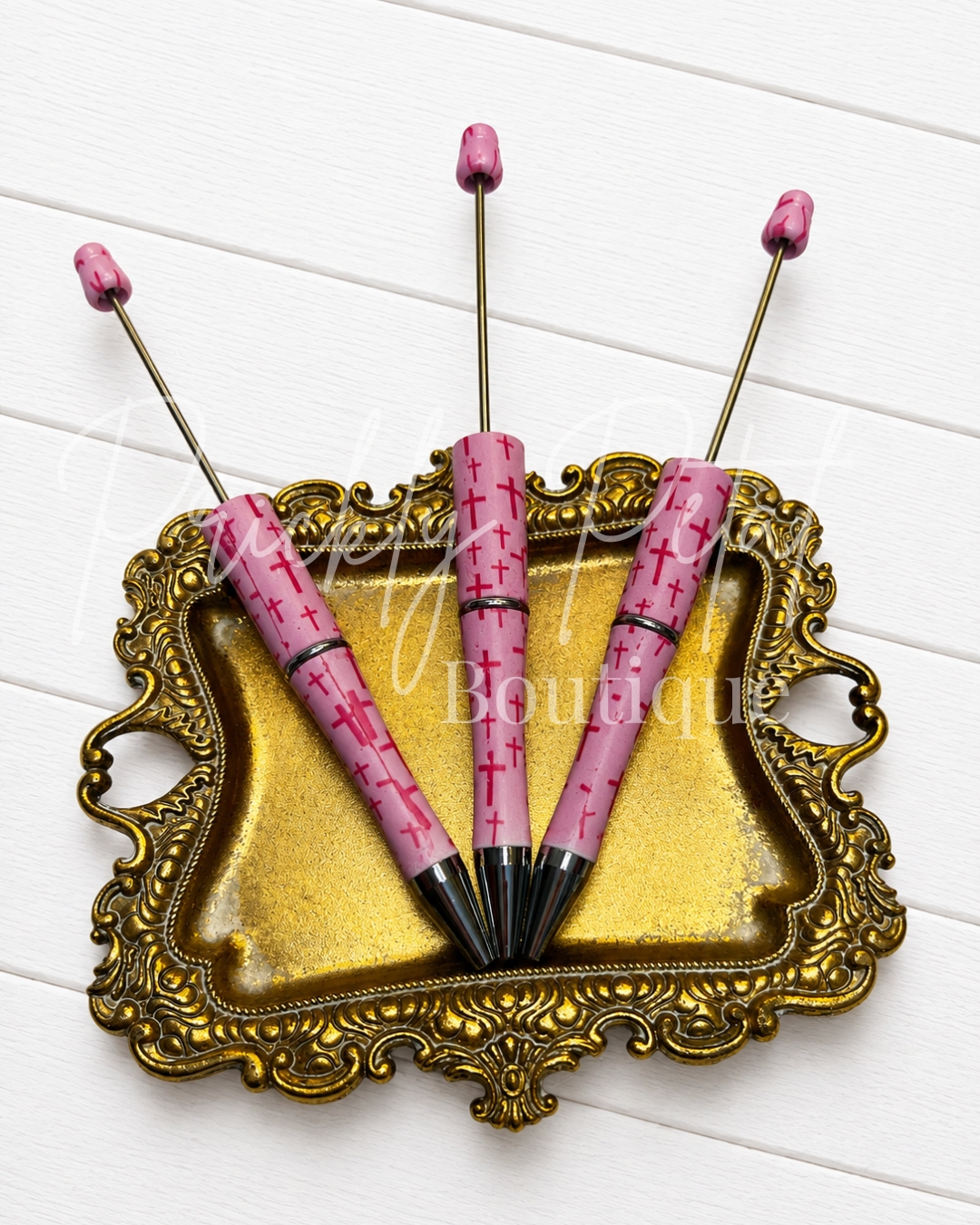 pink cross beadable pen on gold tray against white wood