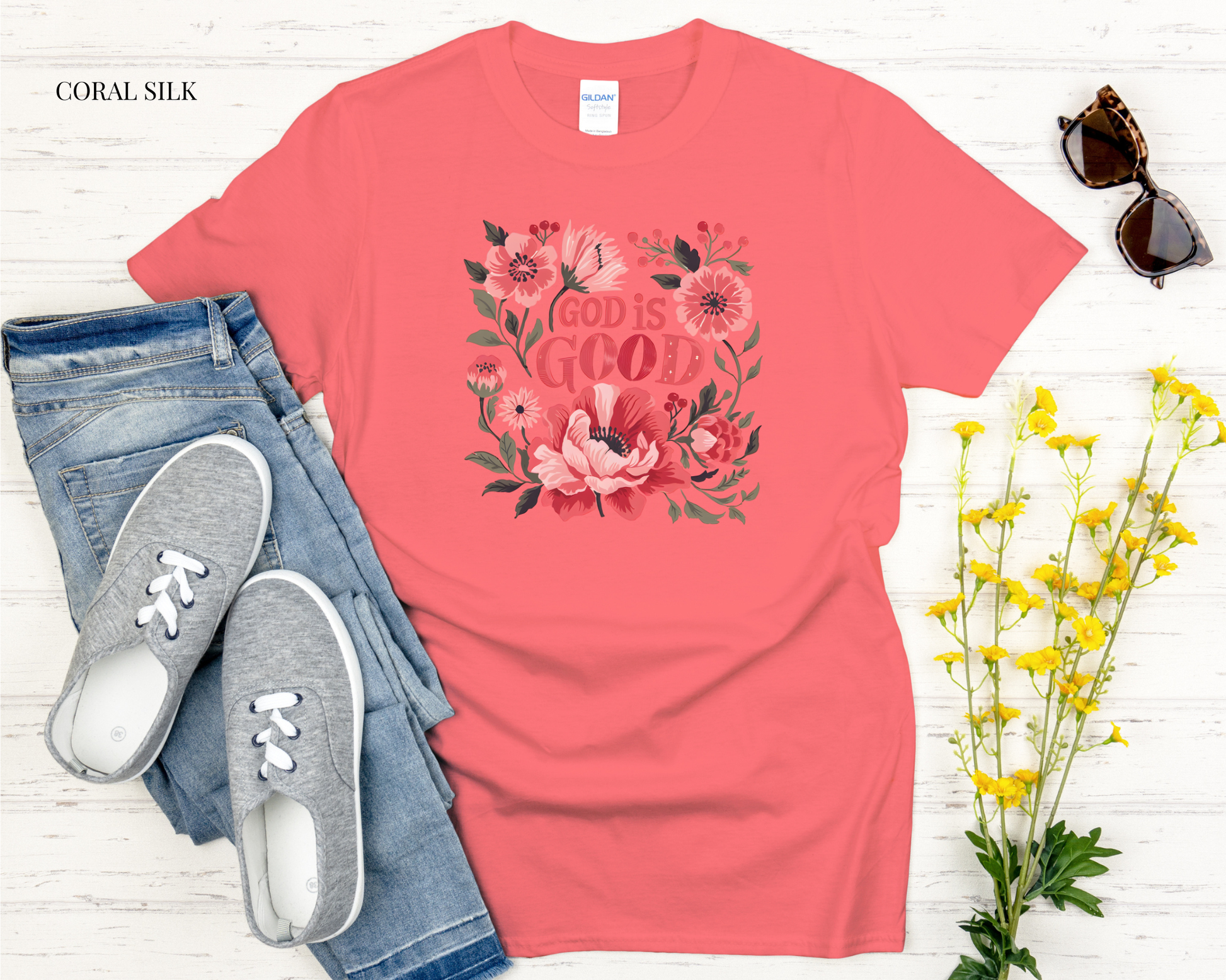 Coral t-shirt with motivational quote, jeans, sneakers, sunglasses, and flowers on a light wooden surface.
