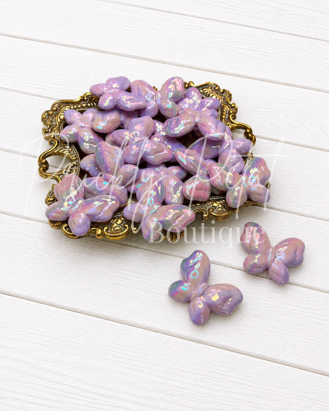 lavender butterfy acrylic bead on gold tray against white wood