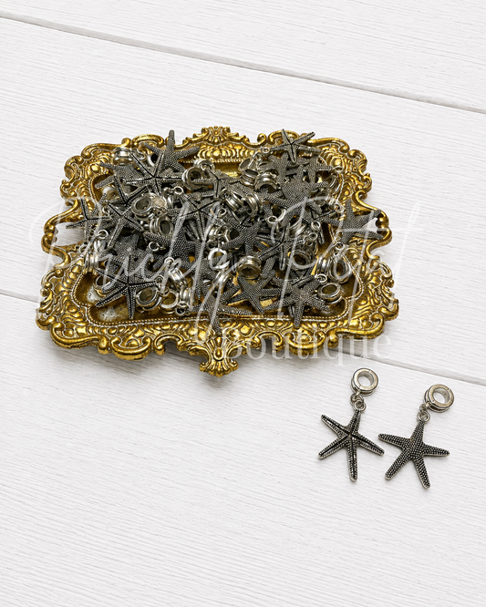 metal starfish pendant charm on gold tray against white wood