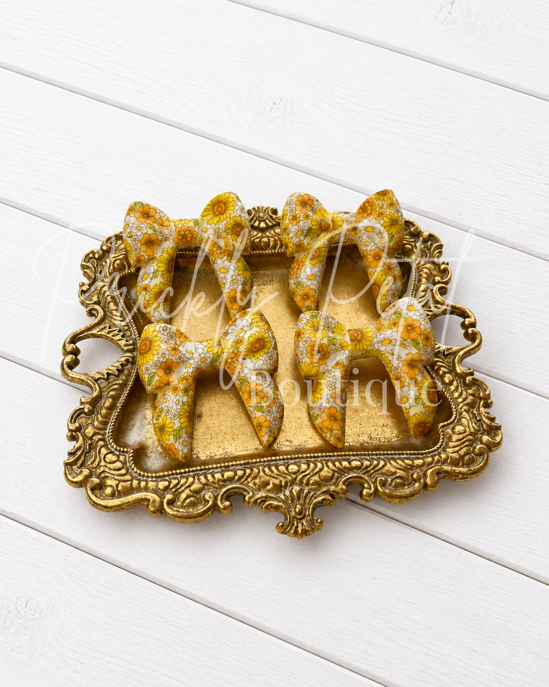 silicone bows arranged on an ornate gold tray, set against a white wood plank background.