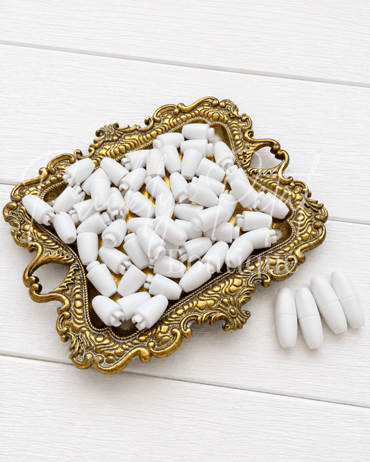 White lanyard clips piled in an ornate gold tray on a white wood surface.